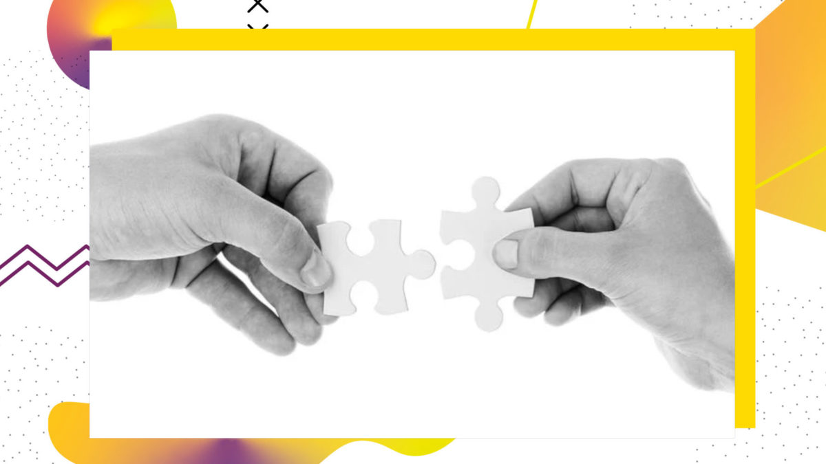 Zwei Hände, die jeweils ein Puzzleteil in der Hand halten, welche zusammen passen